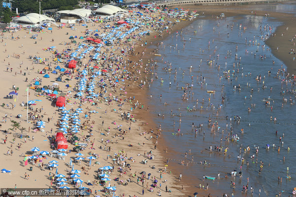 Ba?istas se divierten en Golden Beach (Jinshatan) en Qingdao, una ciudad costera de la provincia de Shandong. Cientos de miles de ba?istas se refrescan en el mar. 17 de agosto de 2014. [Foto/IC]