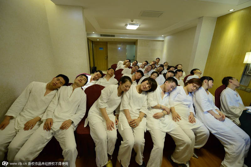 La gente asiste en pijama a una clase para aprender a descargar tensiones con una peque?a siesta en Changsha, provincia de Hunan, el 26 de mayo de 2014. [Foto / PPC]