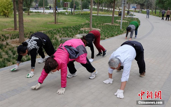 Varias personas caminan “a cuatro patas” en un parque. 