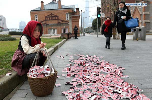 La “peque?a cerillera”se sienta en la zona del Bund de Shanghai, 12 de enero de 2016. [Foto: Xinhua]