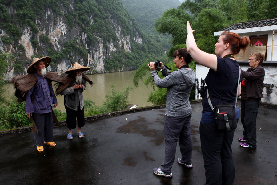 Visitantes de Australia fotografían a los dos ancianos con sombreros tradicionales de bambú en Guilin, región autónoma Zhuang de Guangxi. [Fotografía de Huo Yan/chinadaily.com.cn]