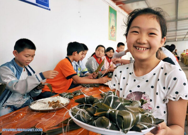 Estudiantes elaboran Zongzi, una bola de masa de arroz glutinoso envuelta en holas de bambú u hojas rojas, con motivo del próximo Festival del Bote de Dragón o Duanwu en chino, en Zaozhuang, provincia de Shandong, en el este de China, el 8 de junio de 2016. El Duanwu se celebrará el 9 de junio este a?o. (Xinhua/Li Zongxian)