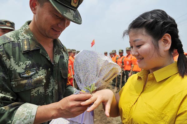 Xu?Hao?coloca?un?anillo?de?hierba en?el?dedo?de?su?novia,?Xiao?Ruoyu,?durante?una?boda?especial?en?una zona afectada por las inundaciones?en Wuwei, ciudad de Wuhu en la provincia?de?Anhui, el 9 de julio de?2016.[Foto/VCG]