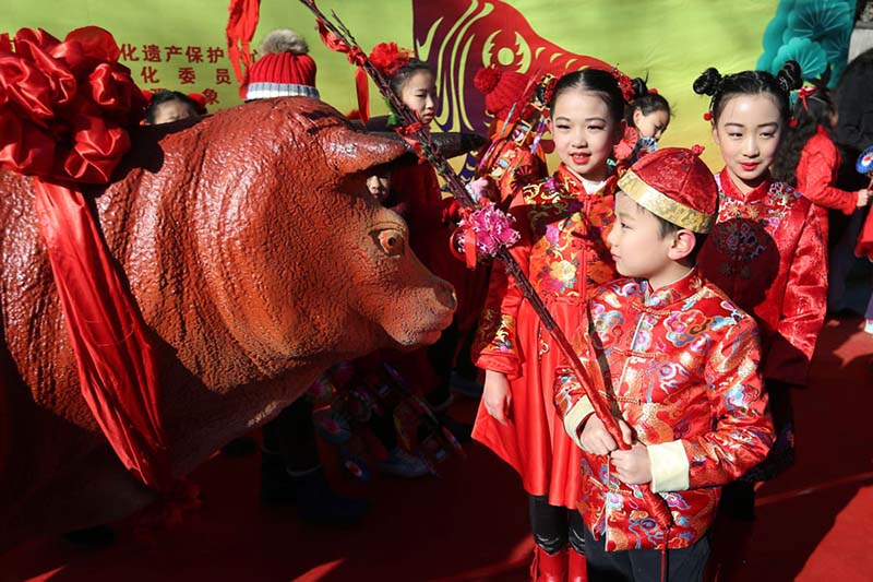 Beijing, 05/02/2018(El Pueblo en Línea) – Un ni?o vestido con un traje tradicional "azota" la figura de un buey con un palo de mimbre en el Observatorio Antiguo de Beijing, el 4 de febrero de 2018. Ni?os azotan figuras de bueyes y juegan con molinetes en el Observatorio Antiguo en Beijing para celebrar el periodo del calendario lunar Comienzo de la Primavera, que comenzó el domingo. [Foto de Wang Zhuangfei / chinadaily.com.cn]