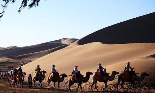 Los turistas visitan la Monta?a Mingsha y el Lago de la Luna Creciente en Gansu 