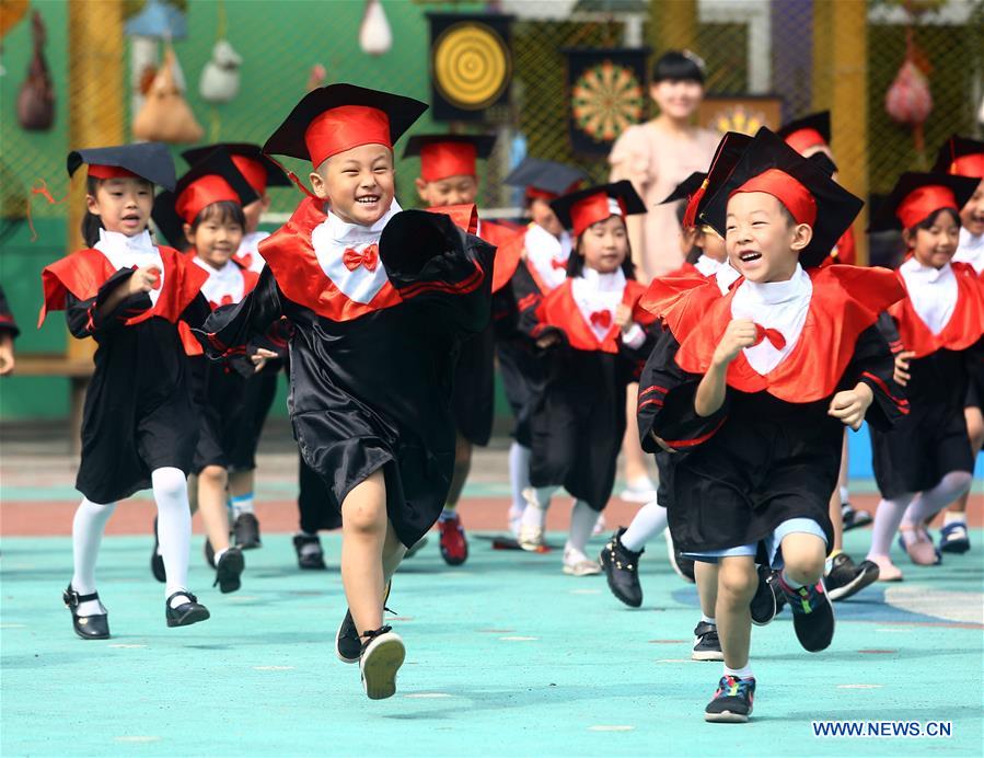 El 17 de junio de 2016, los ni?os de una guardería visten togas de graduación por el patio del centro en el distrito Hedong en Tianjin, China. [Foto / Xinhua]