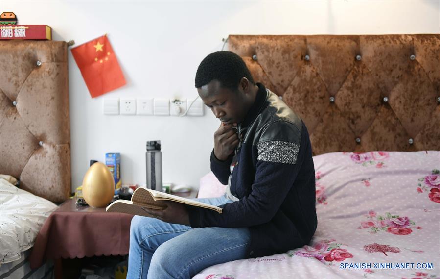  HUNAN, 15 abril, 2019 (Xinhua) -- Imagen del 19 de marzo de 2019, de Mangeh III Fondzenyuy Cedric leyendo un libro en su cuarto, en la Universidad Agrícola de Hunan, en Changsha, provincia de Hunan, en el centro de China. Cedric, de 25 a?os, es de Camerún. Habiendo siendo testigo de la avanzada ciencia agrícola y tecnología y equipo de las empresas chinas, llegó a China en 2017 y estudió un posgrado con especialización en ingeniería de mecanización agrícola en la Escuela de Ingeniería de la Universidad de Hunan después de completar sus estudios de licenciatura. Cedric estudia principalmente mecanización y automatización agrícola, biología moderna, operación y gestión agrícola moderna, extensión de tecnología y ciencia agrícola y otros cursos profesionales en la universidad. Después de estudiar en China durante dos a?os, Cedric no sólo habla chino con fluidez, sino que también aprendió a operar más de 20 tipos de recursos agrícolas, dominó los métodos de manejo de información agrícola y se está convirtiendo en un talento agrícola moderno interdisciplinario. Cedric dijo que después de regresar a Camerún, aplicará lo que aprendió en China a la producción agrícola de su ciudad natal. Como Cedric, cada vez más estudiantes africanos van a Hunan a estudiar en los últimos a?os, especializándose en agronomía, medicina, administración de empresas, ingeniería civil, etc. Mientras aprendían conocimientos profesionales, sintieron el encanto de la cultura china y profundizaron la amistad con profesores y estudiantes de China. (Xinhua/Li Ga)