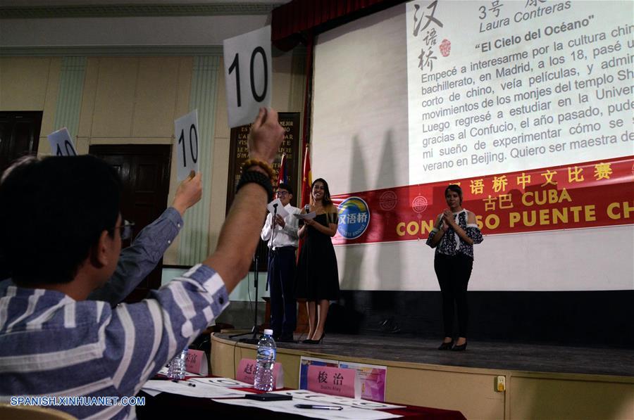 Miembros del jurado califican a Carmen Laura Contreras (d), ganadora de los estudiantes universitarios durante el Concurso Puente Chino Cuba 2019 que se llevó a cabo en un teatro de la Universidad de La Habana, capital de Cuba, el 10 de mayo de 2019. Todos los estudiantes fueron examinados públicamente en dominio del idioma al realizar un discurso; conocimientos sobre China, al responder preguntas sobre el país asiático, y representación artística, con caligrafía, cantos y bailes tradicionales. (Xinhua/Joaquín Hernández)