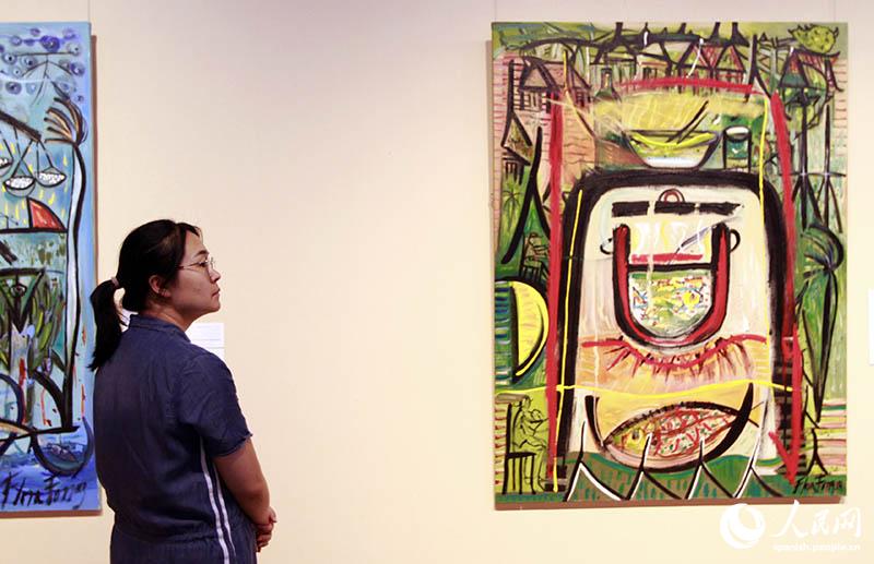 Joven china observa la obra de Flora Fong, “Tong, estar de acuerdo”, durante la inauguración de “El Caribe Ming: imagen, caligrafía y verso”, 26 de junio del 2019. (Foto: YAC)