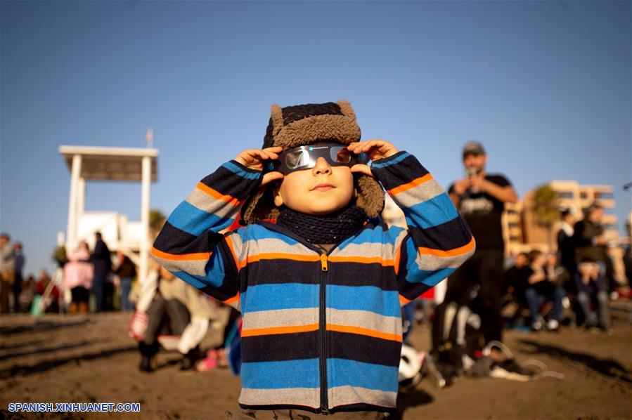 Un ni?o utiliza lentes para observar el eclipse solar total, en la ciudad de La Serena, en la región de Coquimbo, Chile, el 2 de julio de 2019. Miles de personas se aglutinaron en las playas de La Serena y Coquimbo, unos 470 kilómetros al norte de Santiago y a nivel del mar, donde el punto central del eclipse solar total tuvo una duración de dos minutos y 15 segundos. (Xinhua/Jorge Villegas)