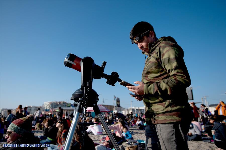 Una persona revisa su teléfono móvil, durante el eclipse solar total, en la ciudad de La Serena, en la región de Coquimbo, Chile, el 2 de julio de 2019. Miles de personas se aglutinaron en las playas de La Serena y Coquimbo, unos 470 kilómetros al norte de Santiago y a nivel del mar, donde el punto central del eclipse solar total tuvo una duración de dos minutos y 15 segundos. (Xinhua/Jorge Villegas)