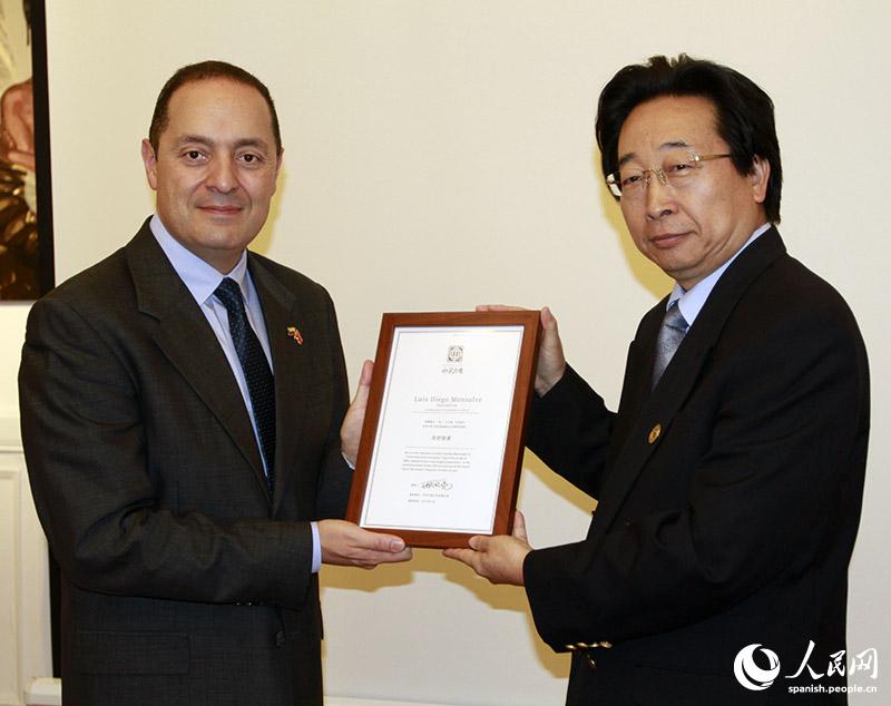 Wang Hua, subsecretario de la Fundación China para la Paz y el Desarrollo, entrega un reconocimiento a Luis Diego Monsalve, embajador de Colombia en China, durante la presentación del nuevo sobre postal artístico, fruto de la colaboración entre ambos países, 11 de julio del 2019. (Foto: YAC)