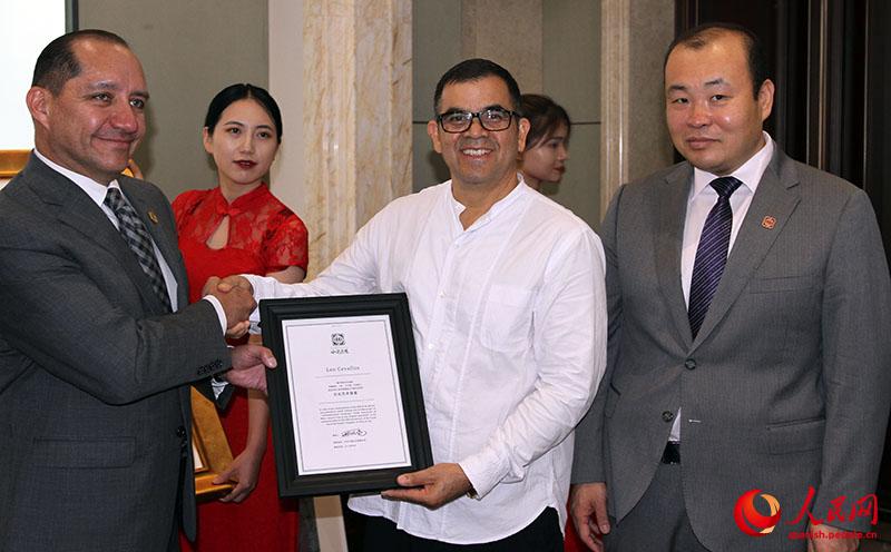 Carlos Larrea (a la derecha), embajador de Ecuador en China, y Xing Fengliang (a la izquierda), fundador de Zhongyulidu Culture, entregan un reconocimiento al maestro Leonardo Cevallos durante la presentación del sobre postal artístico China-Ecuador. Beijing, 9 de agosto del 2019. (Foto: YAC)