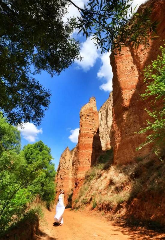 Una turista posa junto a formaciones en el Geoparque de Tierra Roja de Heimapo, Liulin, provincia de Shanxi. [Foto: Wang Fengyun/chinadaily.com.cn]