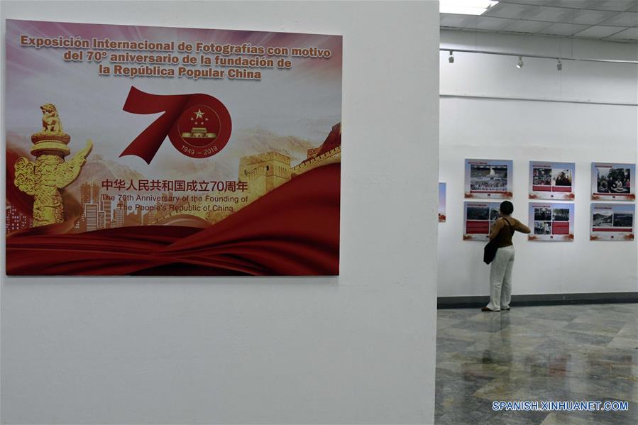 Una mujer observa imágenes de una exposición fotográfica con motivo del 70 aniversario de la fundación de la República Popular China, en la Biblioteca Nacional de Cuba (BNC), en La Habana, capital de Cuba, el 30 de septiembre de 2019. Una exposición que abarca los últimos 70 a?os de historia china se inauguró el lunes en la BNC. (Xinhua/Joaquín Hernández)