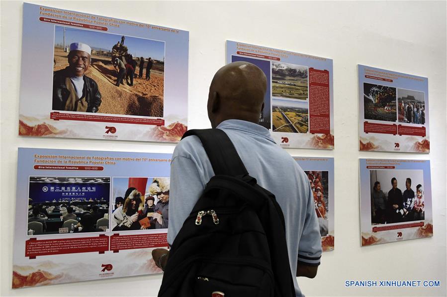 Un hombre observa imágenes de una exposición fotográfica con motivo del 70 aniversario de la fundación de la República Popular China, en la Biblioteca Nacional de Cuba (BNC), en La Habana, capital de Cuba, el 30 de septiembre de 2019. Una exposición que abarca los últimos 70 a?os de historia china se inauguró el lunes en la BNC. (Xinhua/Joaquín Hernández)