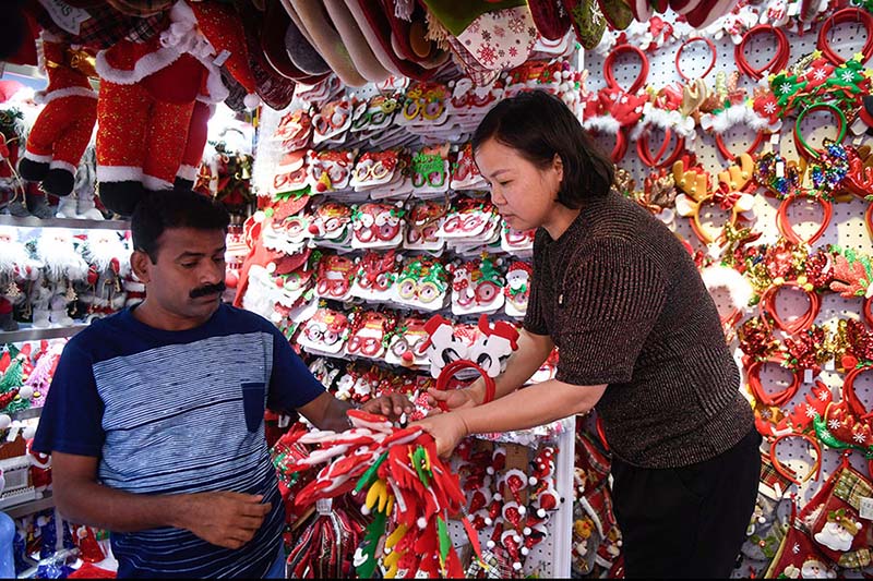 Un vendedor (derecha) muestra decoraciones navide?as en un mercado de la ciudad de Yiwu, provincia de Zhejiang, este de China. [Foto / Xinhua]