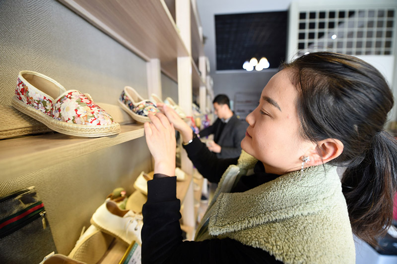 Guo Juan y su esposo, Niu Junjun (en el fondo), organizan un estante de exhibición en su fábrica en el condado Gangu, provincia de Gansu, noroeste de China, el 10 de enero de 2020. [Foto / Xinhua]