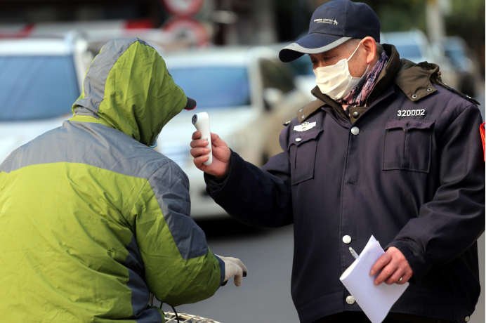 El 2 de febrero de 2020, en la entrada de cada comunidad en el distrito Jianye de Nanjing, había trabajadores y guardias de seguridad de la comunidad trabajando juntos para comprobar la temperatura de las personas que entraban en la comunidad con un detector de temperatura y ofrecer consejos y notificaciones sobre la epidemia. (Yu Tian / vip.people.com.cn)