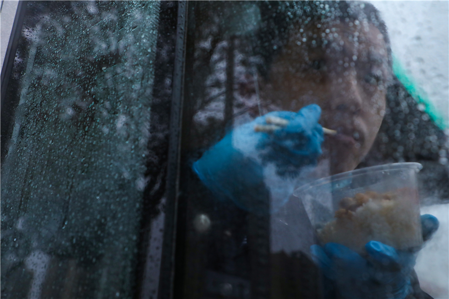 Yan cena una comida rápida en su automóvil policial mientras vigila el tráfico, 6 de febrero del 2020. [Foto: Yuan Zheng / China Daily]