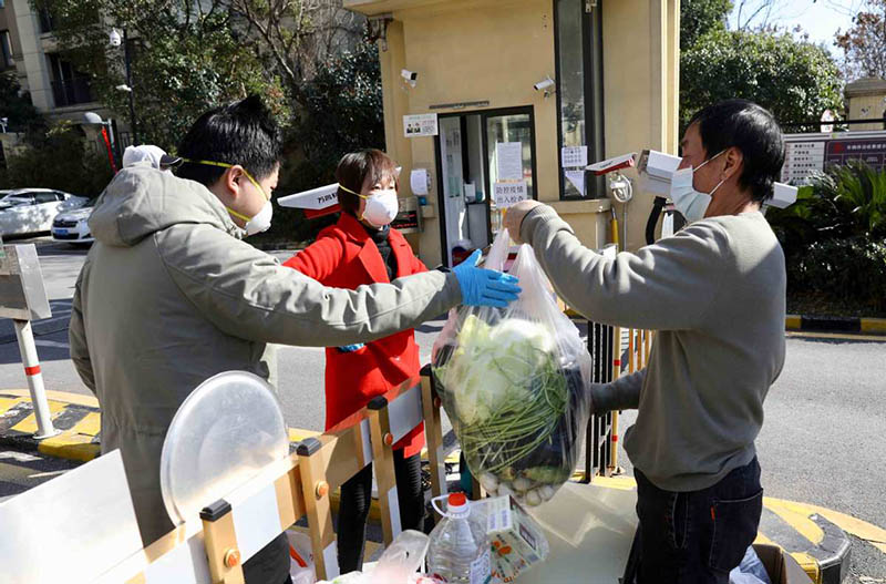 Los residentes buscan las verduras que compraron en la puerta de una comunidad residencial en Wuhan, provincia de Hubei, 18 de febrero del 2020.?[Foto: Zhu Xingxin / China Daily]