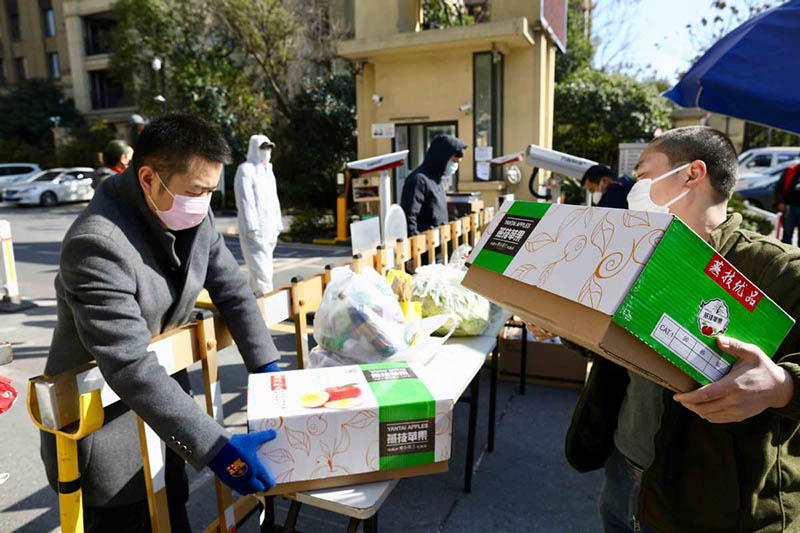 Un hombre trae frutas y las deposita en la puerta de una comunidad residencial en Wuhan, provincia de Hubei, 18 de febrero del 2020.?[Foto: Zhu Xingxin / China Daily]