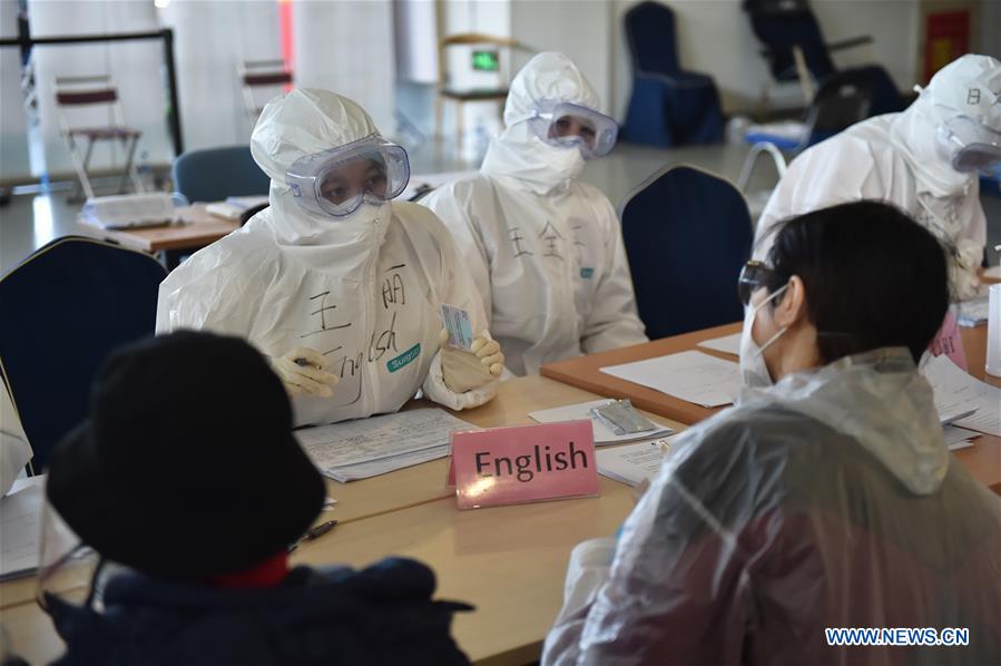 BEIJING, 16 marzo, 2020 (Xinhua) -- Imagen del 14 de marzo de 2020 de trabajadores preguntando información a pasajeros en el Nuevo Centro Internacional de Exposiciones de China en Beijing, capital de China. Beijing ha convertido el Nuevo Centro Internacional de Exposiciones de China en un centro de tránsito para pasajeros entrantes internacionales. (Xinhua/Chen Zhonghao)