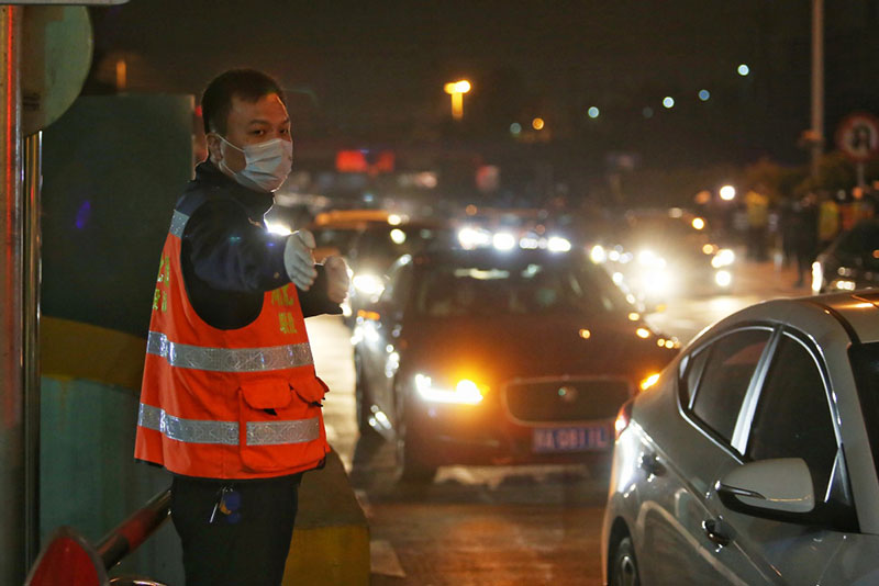 Un empleado ofrece instrucciones a los vehículos que salen de Wuhan, 8 de abril del 2020. [Foto: Chen Liang/China Daily] 