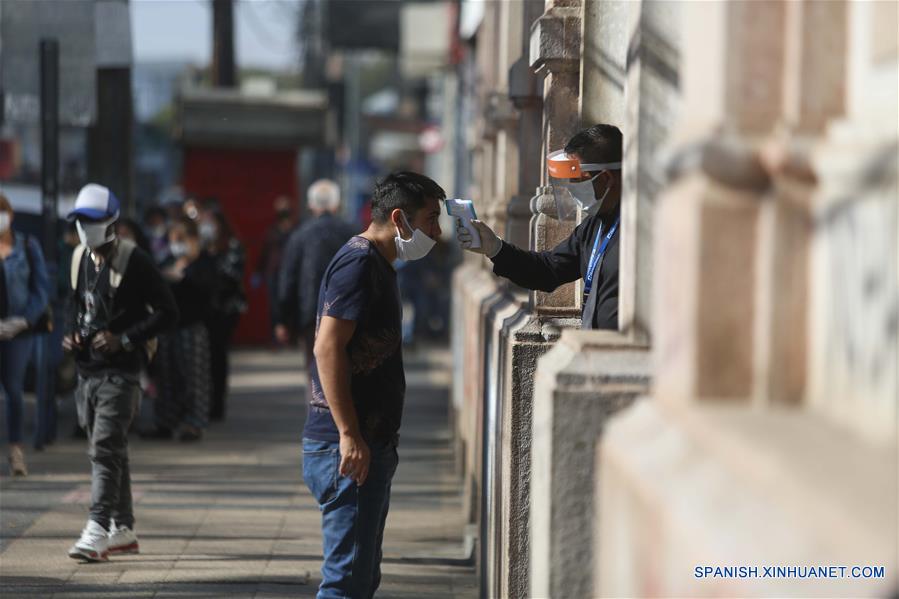 CHILLAN, 22 abril, 2020 (Xinhua) -- Un guardia toma la temperatura corporal de una persona previo a ingresar a una sucursal bancaria, en Chillán, en la región de ?uble, Chile, el 22 de abril de 2020. El Ministerio de Salud de Chile confirmó el miércoles la cifra de 11.296 personas contagiadas con la enfermedad del nuevo coronavirus (COVID-19) en todo el país sudamericano y 160 muertes. (Xinhua/Str) 