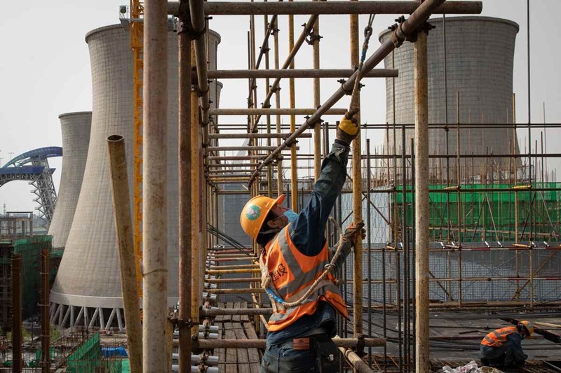 Los trabajadores erigen andamios en el sitio de construcción de un hotel cerca de la Plataforma de Salto de Esquí Shougang en Beijing el 16 de abril. El hotel está siendo construido para los Juegos Olímpicos y se encuentra cerca de la antigua torre de enfriamiento del parque industrial de Shougang. [Foto por Kuang Linhua / China Daily]