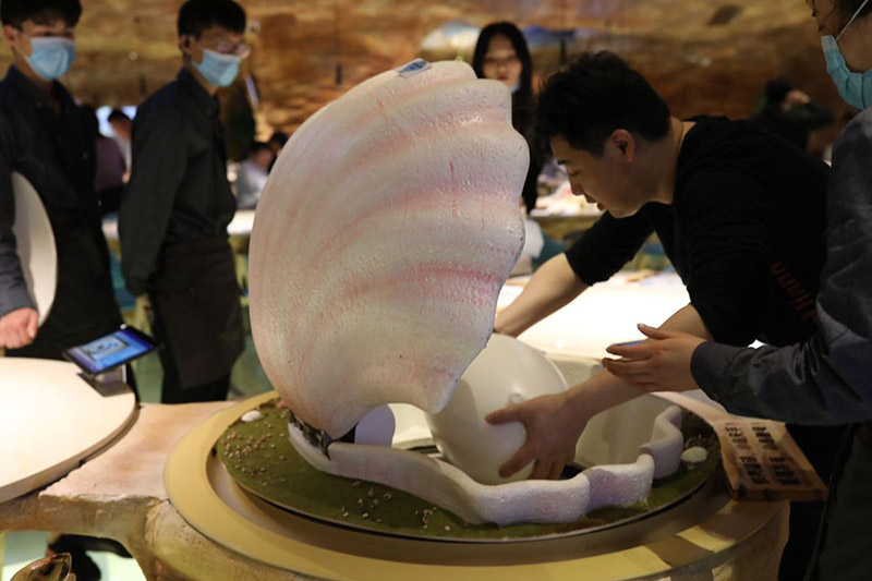 Un camarero sirve comida dentro de un recipiente con forma de perla para los comensales en Caretta Land, un restaurante temático sobre robots tortuga en Shanghai. [Foto proporcionada a chinadaily.com.cn]