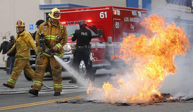 Un bombero extingue un peque?o incendio callejero durante las manifestaciones ocurridas tras la muerte de George Floyd, Los Angeles, California, 30 de mayo del 2020. [Foto: agencias]