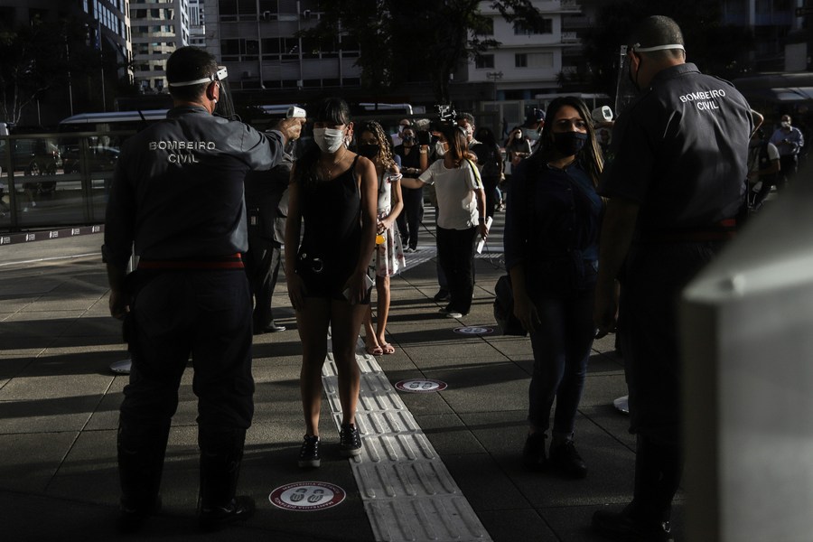 Personas verifican la temperatura corporal de clientes previo a entrar al centro comercial Cidade Sao Paulo durante su reapertura luego de las restricciones de cierre en medio del brote de la enfermedad causada por el nuevo coronavirus (COVID-19), en Sao Paulo, Brasil, el 11 de junio de 2020. (Xinhua/Rahel Patrasso)