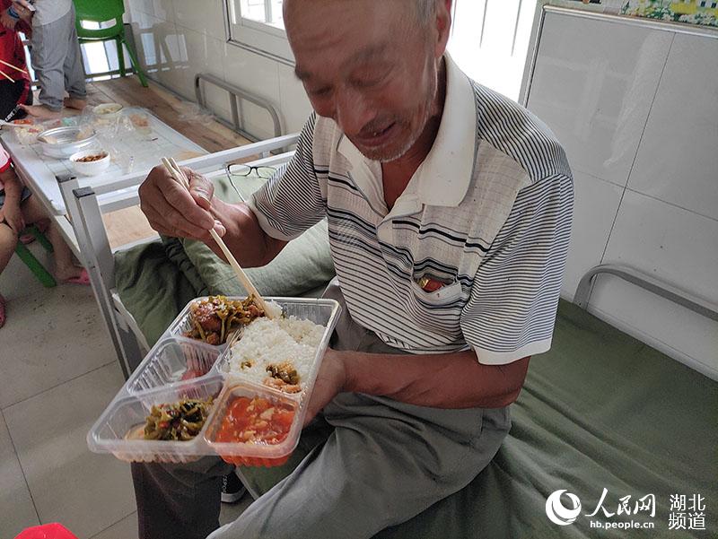 Wu Yunyao disfruta de su almuerzo en el sitio de reubicación. (Foto / Guo Tingting)