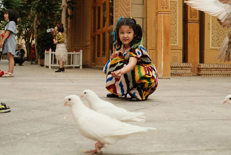 Los ni?os alimentan a las palomas en Tuancheng, la ruta peatonal más famosa en la ciudad de Hotan, en la región autónoma de Xinjiang, en el noroeste de China, el 22 de mayo de 2021 (Pueblo en Línea / Zhang Ruohan).