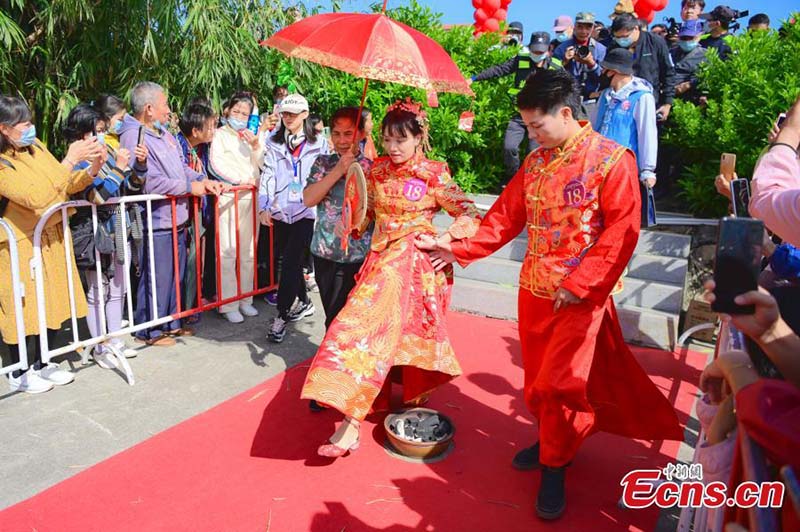 Un novio camina junto a su novia por encima de un candelero. En la boda tradicional china realizar esta acción convoca a eliminar la desgracia durante la vida en pareja, aldea Nanao, distrito de Doumen, Zhuhai, provincia de Guangdong, 24 de octubre del 2021. (Foto: Servicio de Noticias de China/ Chen Jimin)