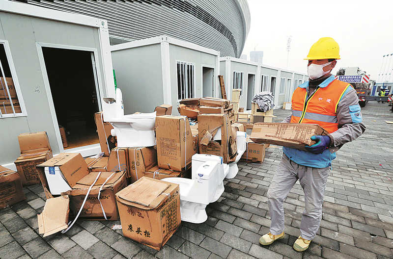 Un trabajador desembala muebles en el sitio de cuarentena temporal fuera de un estadio en Shaoxing, provincia de Zhejiang, el jueves. Se espera que el sitio acomode a 2.500 personas durante su tiempo en cuarentena. [Foto de LIANG YONGFENG / PARA CHINA DAILY]