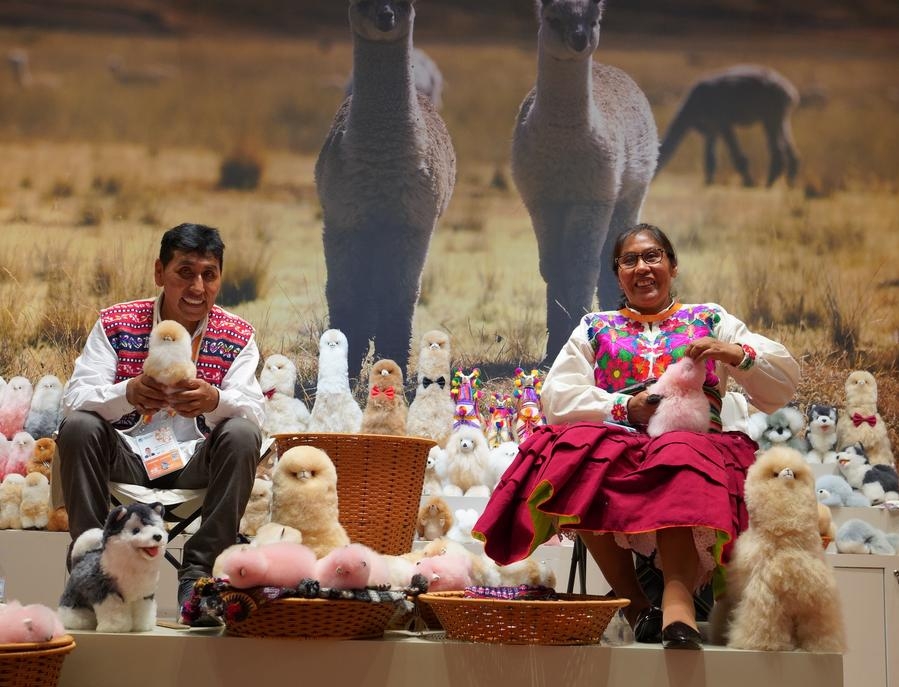 Oswaldo y Gloria, un matrimonio de artesanos de Perú, elaboran peluches de alpaca en el estand de la empresa Warmpaca, durante la sexta edición de la Exposición Internacional de Importaciones de China, en la metrópoli oriental china de Shanghai, el 5 de noviembre de 2023. (Xinhua/Sergio Gómez)